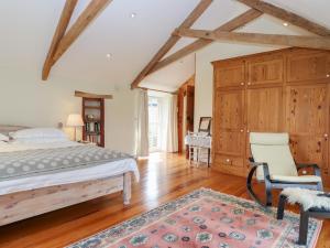 a bedroom with a bed and a chair and a dresser at Monks Cottage in Newton Abbot