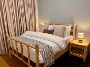 een slaapkamer met een houten bed met witte lakens en kussens bij Andrella Home Arusha in Arusha