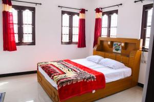 a bedroom with a wooden bed with red curtains at JDP Villa 2 Bhk House in Ooty