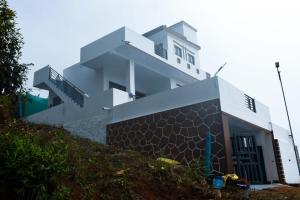 a white house on top of a hill at JDP Villa 2 Bhk House in Ooty