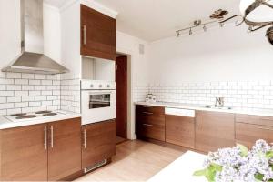 una cocina con armarios marrones y electrodomésticos blancos en Modernt & rymligt sommarhus på landet- Bubbelpool en Eskilstuna