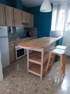 uma cozinha com uma mesa de madeira e um frigorífico em Chez Nanou em Bailleul-sur-ThÃ©rain