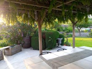 a patio with a table and chairs under a pergola at Chez Nanou in Bailleul-sur-ThÃ©rain