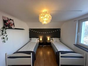 um quarto com 2 camas e um lustre em Modernt & rymligt sommarhus på landet- Bubbelpool em Eskilstuna