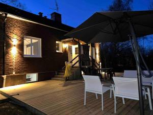 una terraza de madera con 2 sillas y una sombrilla en Modernt & rymligt sommarhus på landet- Bubbelpool en Eskilstuna