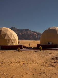 two domes in the desert with a mountain in the background at Scoop Rum in Wadi Rum