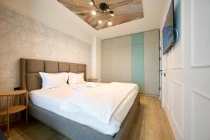 a bedroom with a bed with white sheets and a ceiling at Scorpios in Infinity Pool & Spa Resort in Mamaia Sat/Năvodari