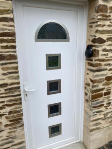 a white door with a window on a stone wall at Chez Flo et Manon in Balleroy