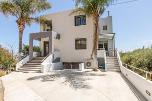a white house with palm trees in front of it at Crystal Waves lux villa-Homeleader in Chania Town