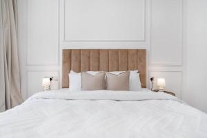 un letto bianco con cuscini bianchi e 2 lampade; di Modern one-bedroom in Arjan - Dubaï a Dubai