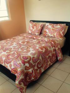 uma cama com um cobertor e almofadas vermelhos e brancos em Sueños del Mar em Fajardo