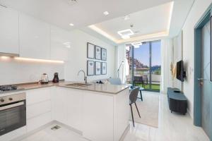 a kitchen with white cabinets and a view of the city at Modern one-bedroom in Arjan - Dubaï in Dubai