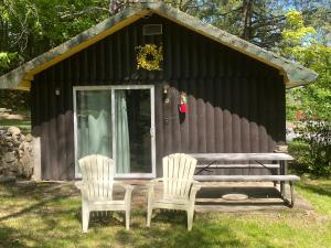 2 Stühle und ein Picknicktisch vor einer Hütte in der Unterkunft Amber Lantern Two-Bedroom Cottage in Lake George