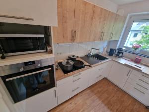 cocina con armarios blancos, fregadero y microondas en Exklusive Ferienwohnung in Meppen, en Meppen