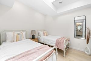 a white bedroom with two beds and a mirror at The Belvedere:Front Street Flats in Belleville