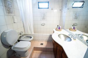 a white bathroom with a toilet and a sink and a toilet istg at Fuxia House Hostel in Mendoza
