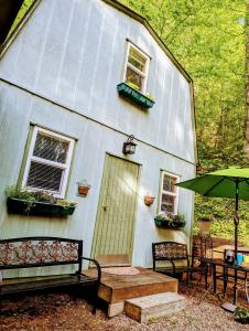 ein weißes Haus mit einem Tisch, Stühlen und einem Sonnenschirm in der Unterkunft Hidden Hollow Bed and Breakfast in Otto