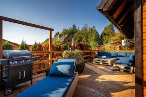 a patio with a grill and blue furniture on a deck at Domek przy morzu in Gąski