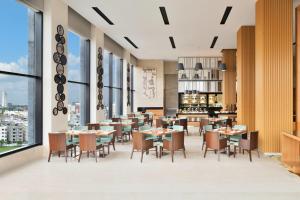 a restaurant with tables and chairs and large windows at Fairfield by Marriott Kolkata in Kolkata