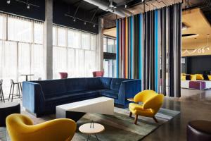 a living room with a blue couch and yellow chairs at Aloft Atlanta Downtown in Atlanta