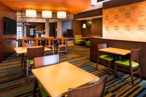 una sala da pranzo con tavoli, sedie e un bar di Fairfield Inn & Suites by Marriott Utica a Utica