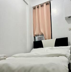 ein weißes Schlafzimmer mit einem Bett und einem Fenster in der Unterkunft Private room with AC and fan at EKG House Rental in Manila