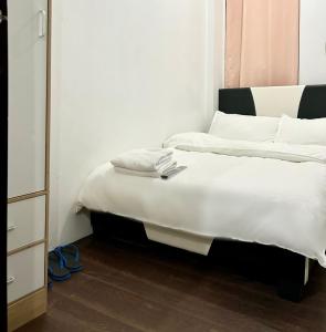 Schlafzimmer mit einem Bett mit weißer Bettwäsche und Kissen in der Unterkunft Private room with AC and fan at EKG House Rental in Manila