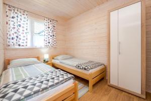 two beds in a small room with wooden walls at Domki Bruno Mare in Bobolin