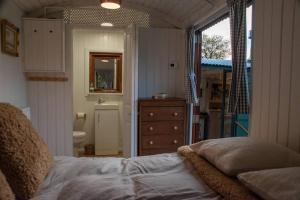 a bedroom with a bed and a bathroom with a sink at Shepherds Hut in enclosed field in Cardiff