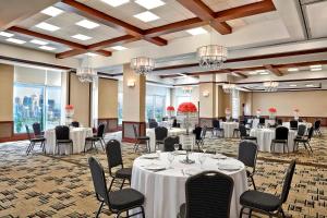 um salão de banquetes com mesas, cadeiras e lustres em Four Points by Sheraton Calgary Airport em Calgary
