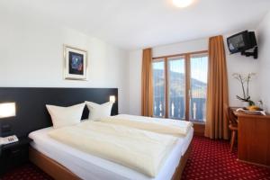 a bedroom with a large white bed and a window at Hotel Central in Obersaxen