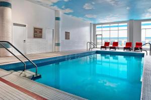 a large swimming pool with blue water and red chairs at Four Points by Sheraton Calgary Airport in Calgary