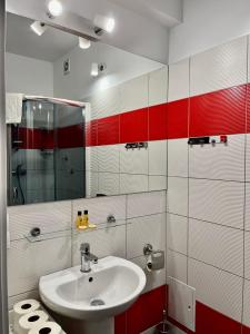 La salle de bains est pourvue d'un lavabo et de carrelage rouge et blanc. dans l'établissement Apartament 205 Planeta Mielno 100 m od plaży, à Mielno