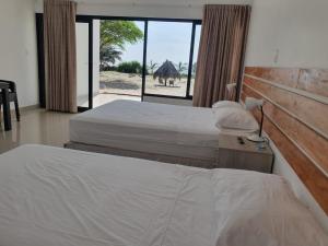 a bedroom with two beds and a window with a camel outside at Las Hamacas in Canoas de Punta Sal