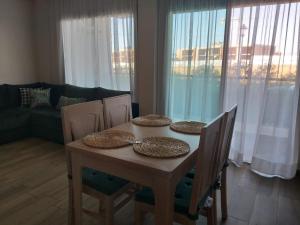 a dining room table and chairs with a table and a couch at Sidi Rahal Blue Beach Appartement Pieds Dans L'eau in Sidi Rahal