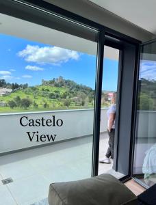 eine Person, die auf einem Balkon mit Blick auf eine Glastür steht in der Unterkunft Castelo View in Pombal