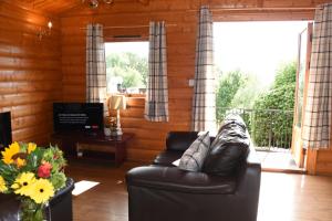 sala de estar con sofá de cuero y balcón en Tawny Owl Lodge, en Rhayader