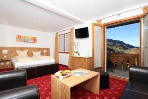 a hotel room with a bed and a table and chairs at Hotel Central in Obersaxen