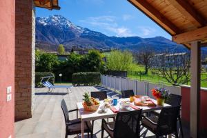 a table and chairs on a patio with mountains in the background at Residence Girasole Casa Rossa B in Colico