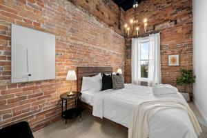 a bedroom with a brick wall and two beds at The Goodman: Front Street Flats in Belleville
