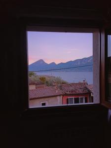 a window with a view of a building and water at Appartamento con vista Lago Casa Gaspar in Brenzone sul Garda