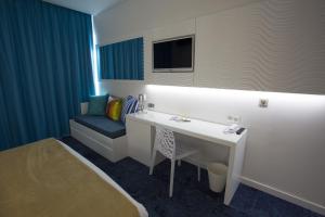 a room with a desk and a chair and a tv at Marineland Hôtel in Antibes