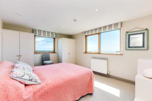 a bedroom with a pink bed and two windows at Dolphins in Coverack