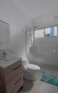 a white bathroom with a toilet and a sink at Villa Golden Dream in San Felipe de Puerto Plata