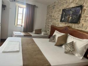 a bedroom with two beds and a stone wall at Hotel Omer The Ottoman House in Berat