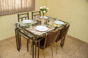 una mesa de cristal con sillas y platos y un jarrón de flores en Casa espaçosa e confortável na região da Pampulha, en Belo Horizonte