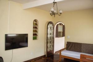 a living room with a tv and a couch and a window at Casa espaçosa e confortável na região da Pampulha in Belo Horizonte