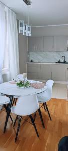 eine Küche mit einem weißen Tisch und weißen Stühlen in der Unterkunft Cosmopolitan Apartament z bezpłatnym, prywatnym parkingiem w hali garażowej in Toruń