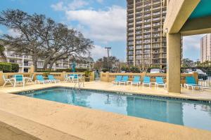 a swimming pool with blue chairs and a building at Myrtle Beach Condo with Ocean View and Pool Access! in Myrtle Beach