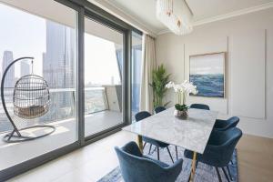 a dining room with a table and chairs and large windows at LARBI Breathtaking Burj and Fountain View Luxurious 2 Bed in Dubai